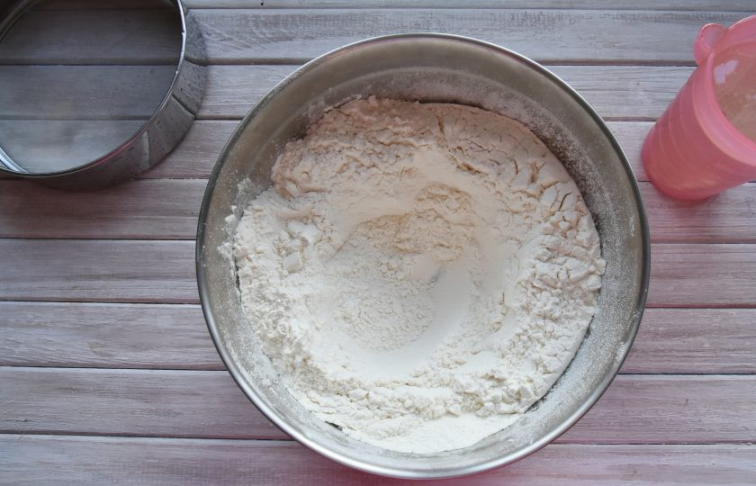 1. Этап. Момо с курицей: В подходящую по размеру миску пересыпьте муку и сделайте в ней углубленее в центре по типу воронки.