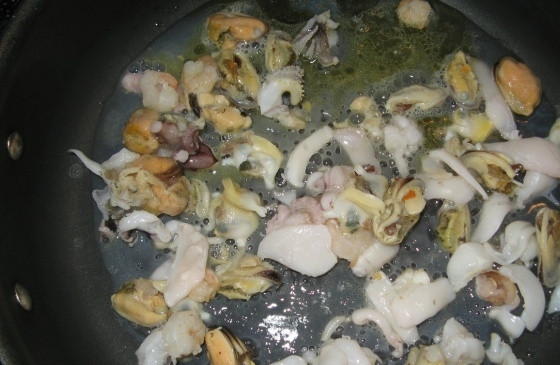 1. Этап. Плов с морепродуктами: В сковороде разогреваем оливковое масло и обжариваем на нем морской коктейль в течение 5-7 минут на сильном огне посолив. Потом перекладываем на отдельную тарелку.