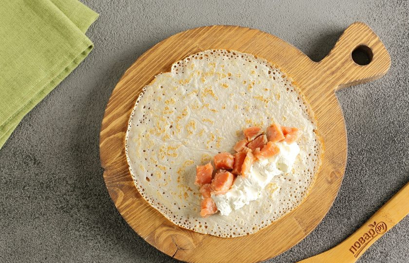 1. Этап. Блины на праздничный стол: Выложите блинчик на ровную поверхность. Ближе к одному краю распределите начинку.