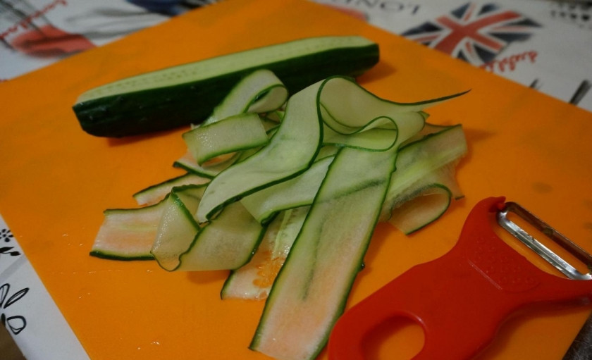 1. Этап. Блинные роллы со сливочным сыром и красной рыбой: Огурец помойте. Нарежьте его овощерезкой очень тонкими слайсами.