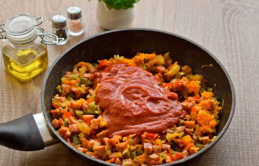 1. Этап. Рассольник с копченой колбасой и перловкой: Томатную пасту соедините с водой, примерно 70 мл. Жарьте овощи с колбасой и огурцами 4-5 минут, затем добавьте томат и щепотку сахарного песка, для баланса вкуса. Тушите все в течение 5 минут, под крышкой.