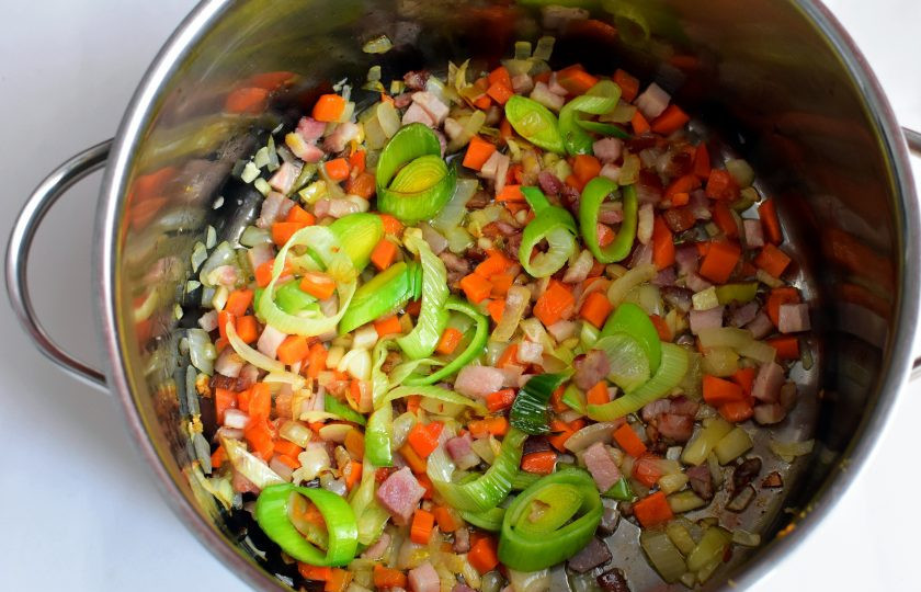 1. Этап. Риболлита: Нарежьте некрупными кубиками копченую грудинку и выложите в кастрюлю с толстым дном. Добавьте немного оливкового масла. Нашинкуйте средними кубиками лук, лук-порей, морковь и чеснок. Прогрейте овощи на небольшом огне, помешивая, минут 10.