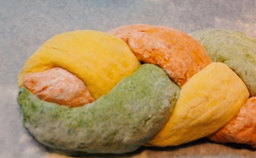 1. Этап. Трёхцветный хлеб с натуральными красителями: 4. Когда тесто приподнялось, раскатайте каждый кусочек в продолговатую колбаску. Выложите их на пергаментную бумагу и сплетите косичку (но не очень тугую). Накройте косичку полотенцем на 20-30 минут. Как только тесто приподнялось, смажьте его с помощью кисточки водой и посыпьте маком, кунжутом и семечками.