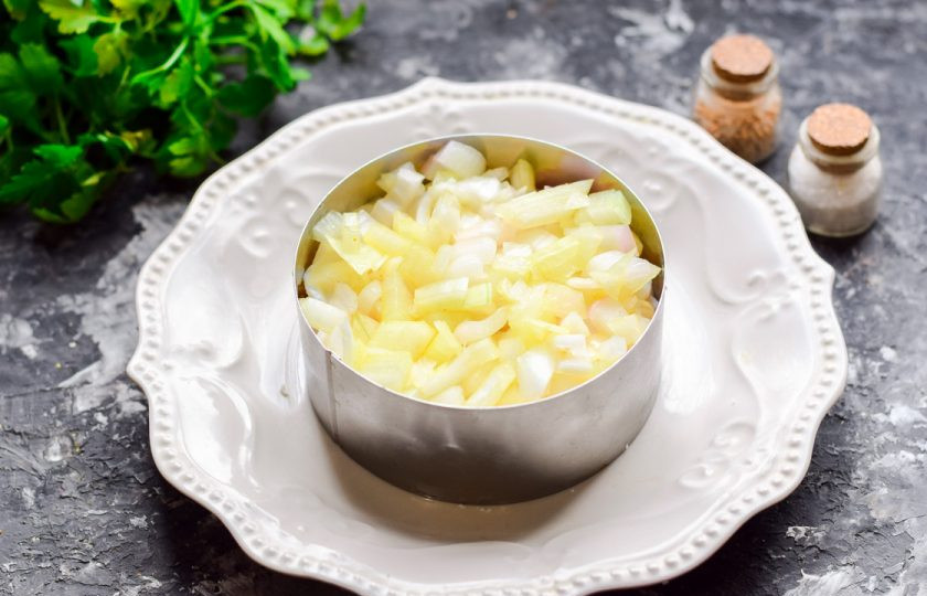 1. Этап. Салат Мимоза с кальмарами: Очистите лук, нарежьте небольшими кубиками и замаринуйте в уксусе. Лук выложите поверх кальмаров.