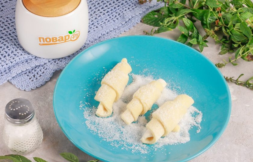 1. Этап. Творожные рогалики Нежнее нежного: Высыпьте оставшийся сахар на тарелку и обпанируйте в нем заготовки рогаликов.
