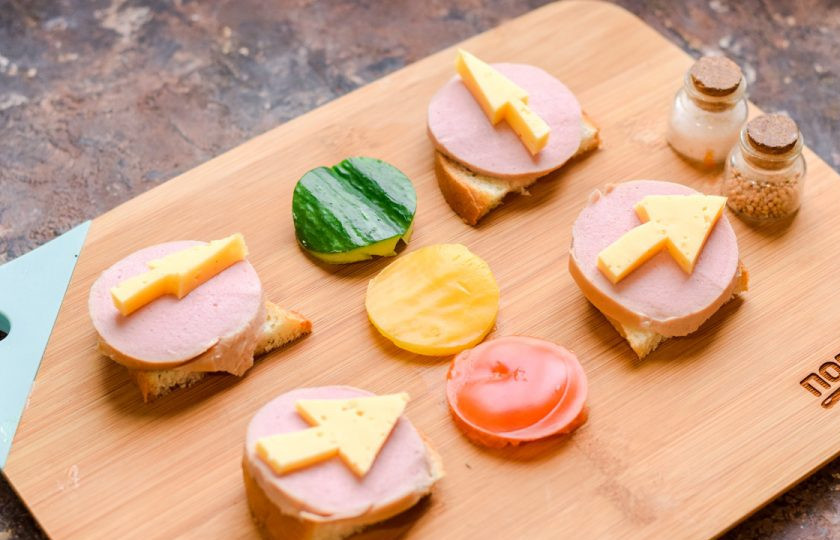 1. Этап. Бутерброды Дорожные знаки: Из твердого сыра вырежьте острым ножом дорожные знаки, стрелочки, которые регулируют движение, разложите их поверх колбасы.