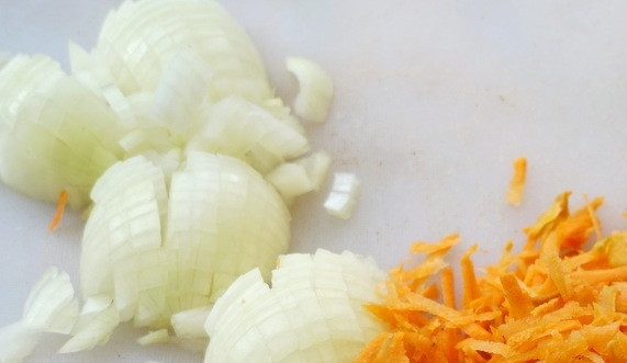1. Этап. Тушеная капуста в казане со свининой: Лучок и морковку очистите. Нарежьте ножом и натрите на терке овощи.