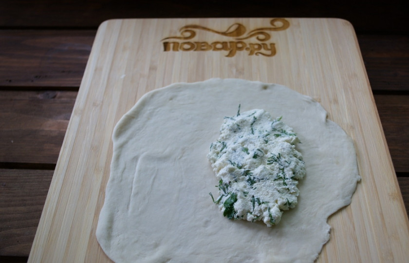 1. Этап. Чебуреки с творогом и зеленью: Каждый кусочек теста раскатайте в пласт. На одну сторону пласта выложите столовую ложку начинки.
