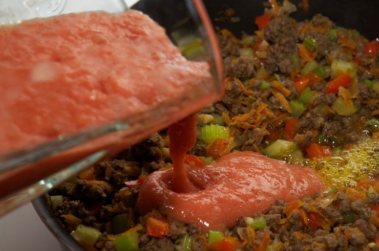 1. Этап. Лазанья с фаршем и овощами: 5. Помидоры очистите от кожицы и взбейте в блендере. Вылейте на сковороду. Добавьте соль, перец, специи по вкусу.