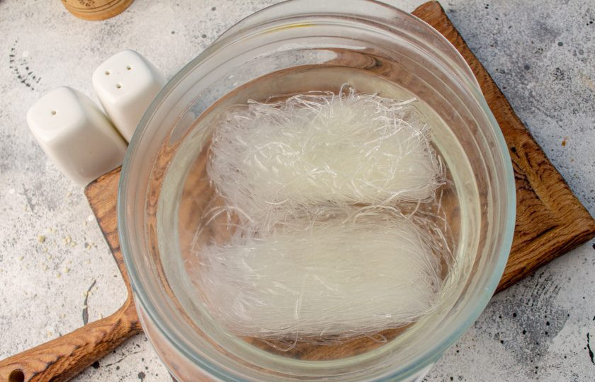 1. Этап. Салат по-китайски Харбинский: Фунчозу (рисовую лапшу) выложите в подходящую тару, залейте кипятком и оставьте на 10 минут.