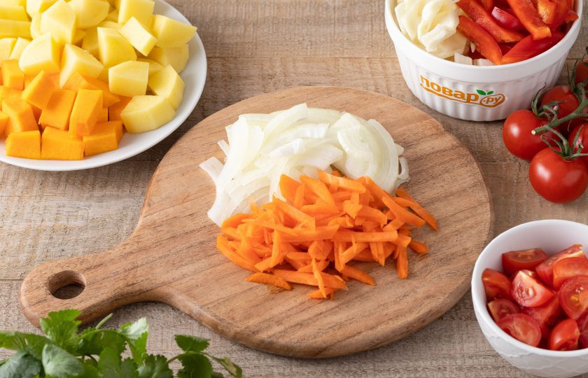 1. Этап. Овощное рагу по-домашнему: Репчатый лук нарежьте полукольцами, а морковь очистите и натрите на терке. Картофель и тыкву очистите от кожуры и порежьте на кубики среднего размера. Помидоры разрежьте на 2-4 части, а капусту и болгарский перец порежьте на ломтики среднего размера.