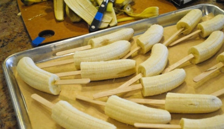 1. Этап. Десерт Бананы в шоколаде: 1. Фрукты очищаем от кожуры и разрезаем на половинки, каждую надеваем на палочку.