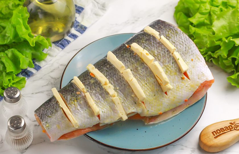 1. Этап. Горбуша со сливочным сыром в духовке: Нарежьте плотный сливочный сыр и выложите его в разрезы на тушке.