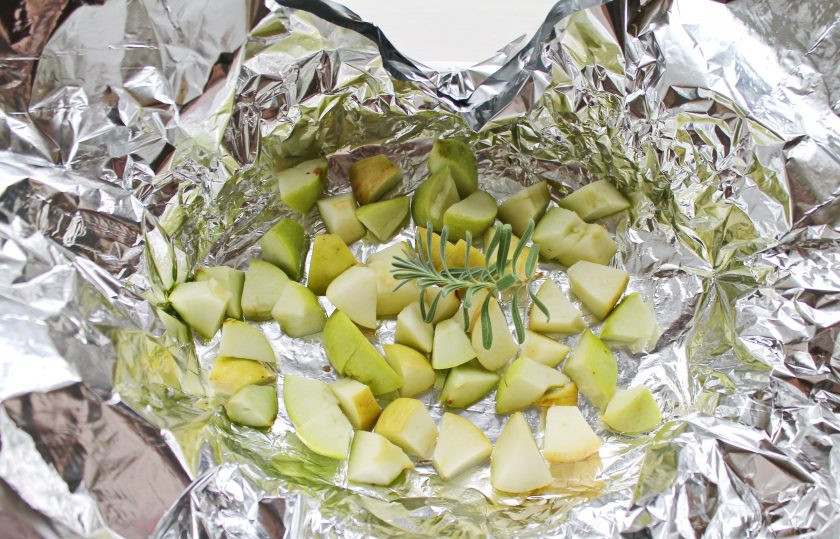 1. Этап. Буженина с яблоками: Сложите фольгу в 3-4 слоя, и выложите на нее порезанные кубиком яблоки и веточку розмарина.