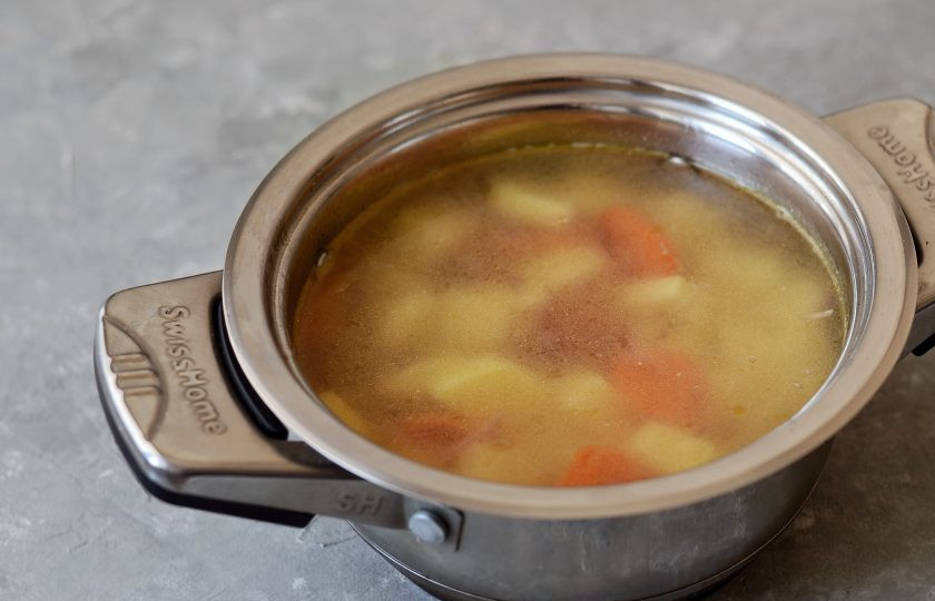 1. Этап. Арахисовый суп: Налейте воду в кастрюлю. Добавьте картофель порезанный кубиками, лавровый лист, посолите и поперчите. Доведите до кипения, убавьте огонь и варите суп примерно полчаса.