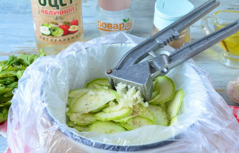 1. Этап. Быстрая засолка кабачков в пакете: Выдавите к кабачкам чеснок.