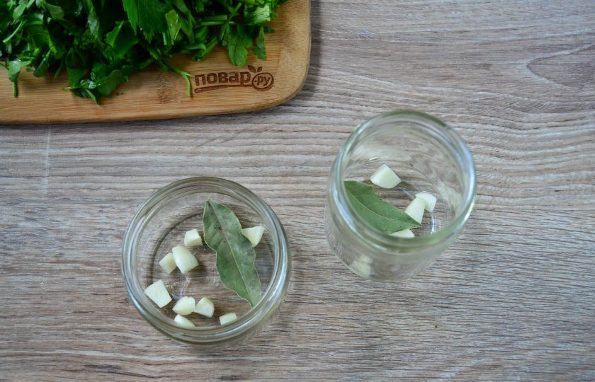 1. Этап. Маринованная петрушка: На дно чистых банок положите нарезанный чеснок и по лавровому листику.