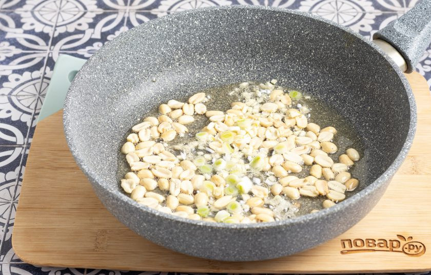 1. Этап. Фасоль с арахисом: Добавьте порубленный чеснок и белую часть зеленого лука. Потомите около минуты все вместе.