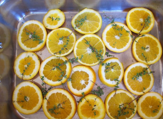 1. Этап. Глазированные куриные ножки: 3. Затем нарежьте апельсин кружками. Выложите их в форму для выпечки. По фруктам разложите веточки тимьяна.