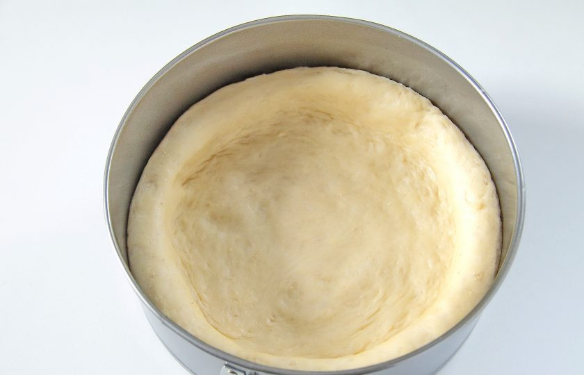 1. Этап. Домашняя ватрушка с шоколадной стружкой: 7. Переложите тесто в смазанную маслом форму и руками придайте ему форму лепешки с бортиками, высотой около 2 см. Накройте и оставьте примерно на 20 минут.