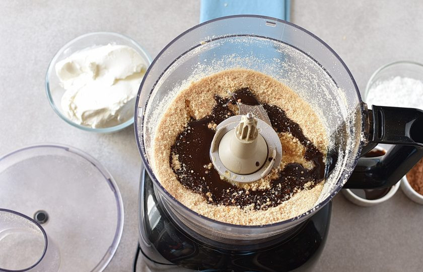 1. Этап. Шоколадный Чизкейк: В блендере измельчите печенье в пульсовом режиме в крошку. Влейте растопленное сливочное масло, добавьте 2 ложки шоколадного сиропа и еще раз пробейте в блендере. Смесь должна напоминать влажный песок.