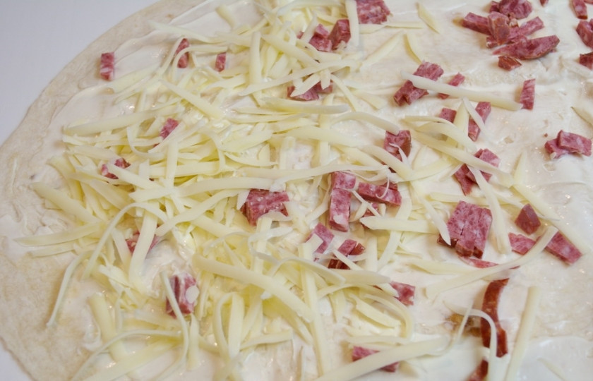 1. Этап. Жареный лаваш с колбасой и сыром: На крупной терке натрите твердый сыр. Выложите равномерно на лаваш.