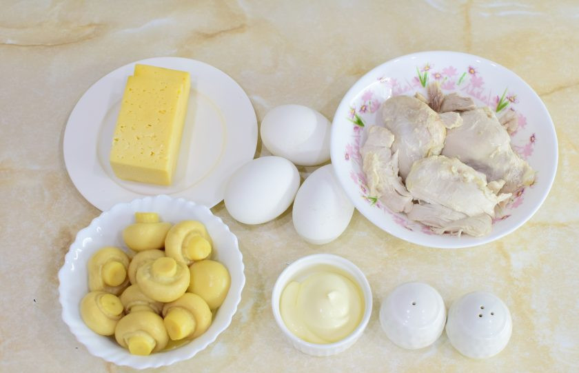 1. Этап. Салат с курицей, сыром и маринованными грибами: Для приготовления салата подготовьте все необходимые ингредиенты. Заранее отварите куриное мясо и яйца. Остудите.
