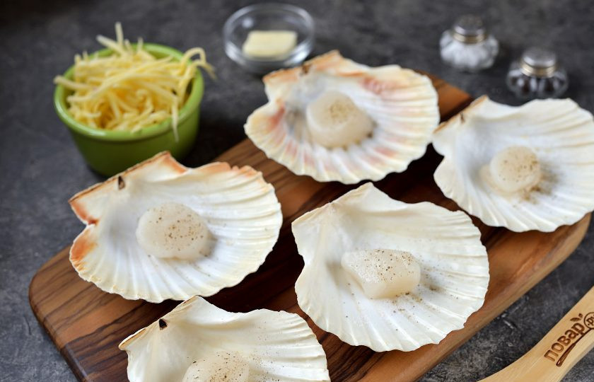 1. Этап. Гребешки в раковинах под сыром: Выложите гребешки в ракушках на разделочную доску, мясо посолите и поперчите по вкусу.