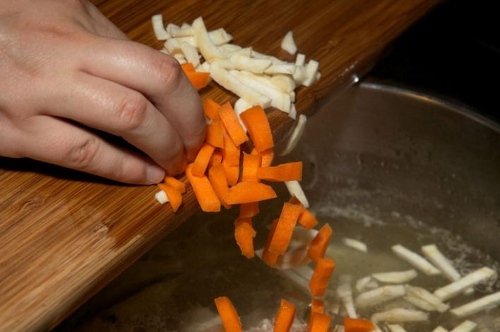 1. Этап. Суп из крапивы и щавеля: Нарежьте брусочками корень петрушки и морковь, добавьте в бульон.