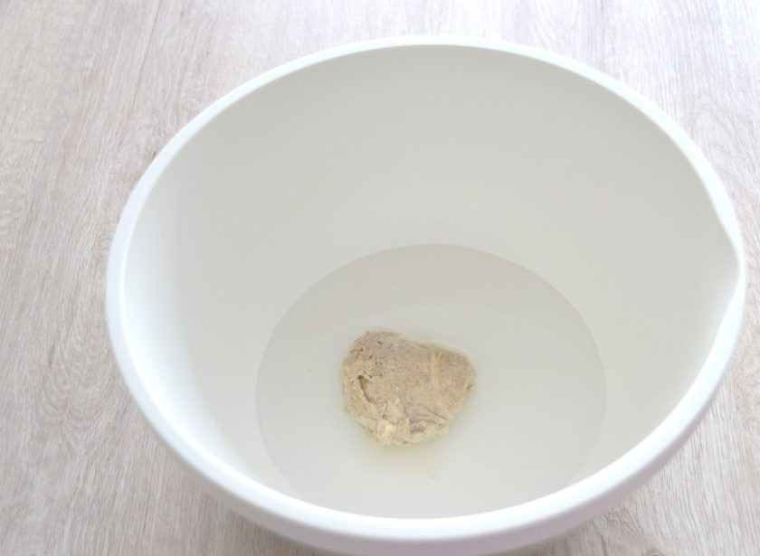 1. Этап. Пшеничный хлеб на ржаной закваске: В емкость для замешивания теста влейте воду комнатной температуры, добавьте ржаную закваску, сахар, 2-3 ст. ложки муки от общего количества. Смешайте до однородности, накройте крышкой и оставьте для брожения на 30 минут.