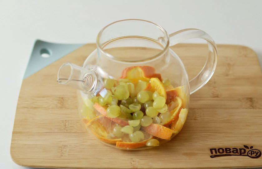 1. Этап. Виноградный чай: Ягоды винограда разрежьте пополам, переложите в чайник с апельсином.