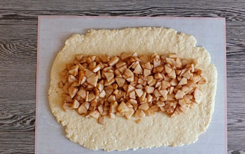 1. Этап. Творожная плетенка с яблоками: В середину пласта, отступая от краев по 10 см., выложите яблочную начинку. Выделившийся сок слейте.