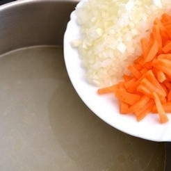 1. Этап. Суп с рисом и картошкой: Вынуть курицу из бульона. И сразу же в бульон положить лук и морковь.