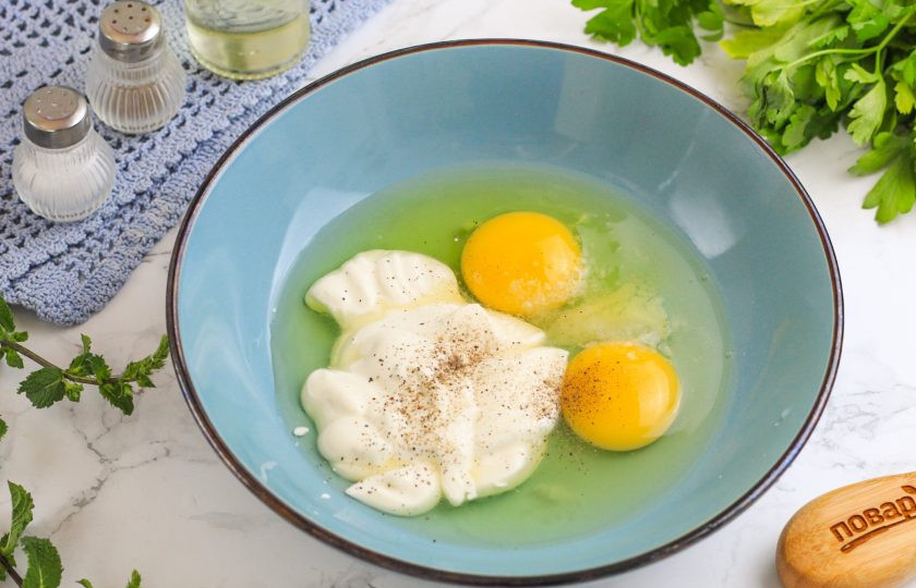 1. Этап. Пирог с солеными грибами: Вбейте куриные яйца в глубокую емкость и добавьте сметану, соль и молотый перец. Тщательно взбейте и добавьте воду. Еще раз взбейте.