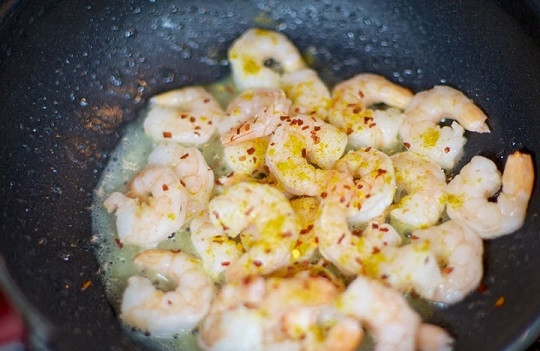 1. Этап. Салат с жареными креветками: 2. Параллельно поставьте на огонь большую кастрюлю с водой, доведите до кипения. Обжарьте креветки на протяжении нескольких минут, затем добавьте специи (использовать вы можете в этом простом рецепте салата с жареными креветками все, что пожелаете), в данном случае это хлопья перца чили.