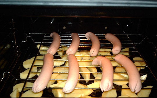 1. Этап. Картофель с сосисками в духовке: 4. Поставить противень в духовку на низ, а сверху установить решетку. Выложить на нее сосиски. При желании их также можно взбрызнуть растительным маслом.