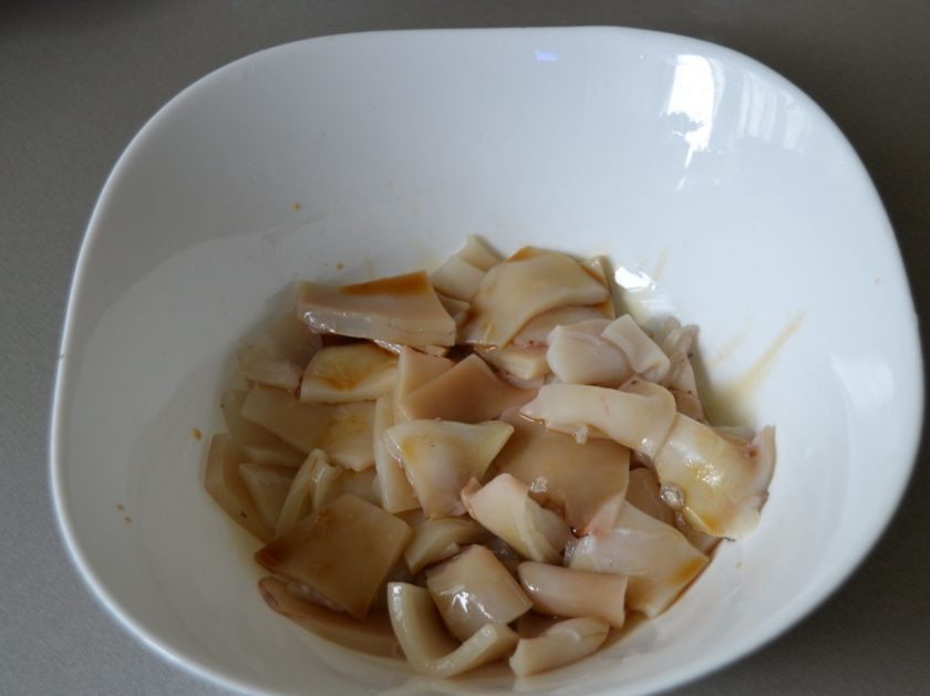 1. Этап. Кальмары в чесночном соусе: Нарежьте кальмары ломтиками и сбрызните их 1 ст. ложкой соевого соуса.