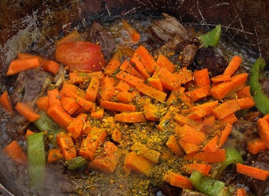 1. Этап. Шурпа из баранины в казане: Через минутку, как перемешаем, добавляем морковь, кориандр, зиру, куркуму, соль и перец.