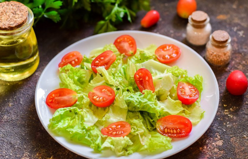 1. Этап. Салат с тунцом и кедровыми орешками: Помидоры черри сполосните и просушите, нарежьте помидоры дольками, выложите поверх салатных листьев.