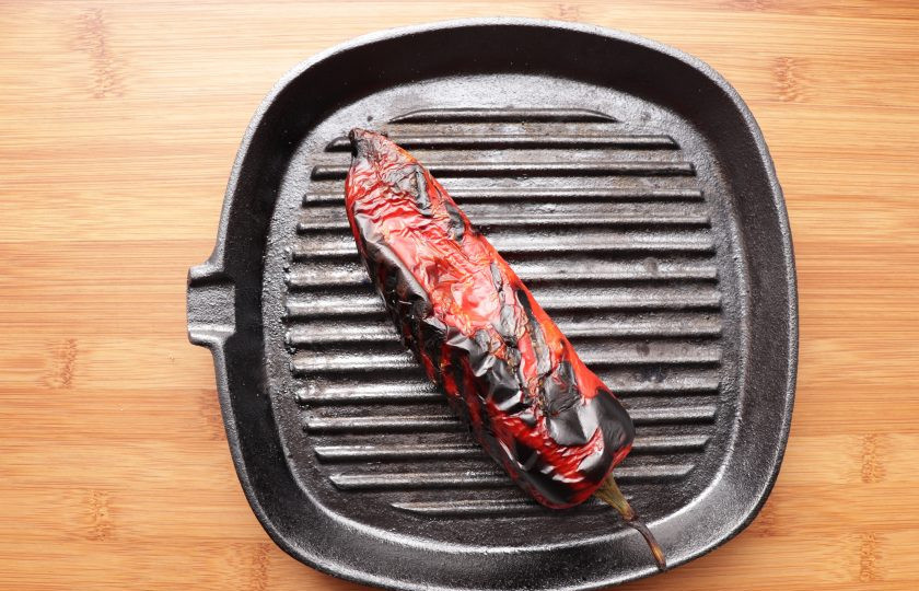 1. Этап. Кальмары с творогом: Перец запеките на сковороде гриль или в духовке. Готовый перец переложите в кастрюлю, накрыв крышкой. Затем снимите с перца кожицу, очистите от семян и нарежьте небольшими кусочками.