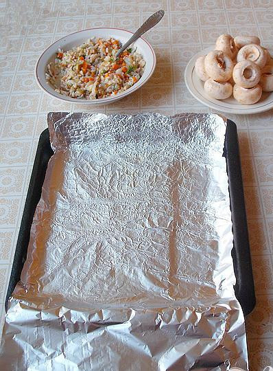 1. Этап. Фаршированные шампиньоны в фольге: 4. Смешиваем тушеные овощи и рис, перчим и солим, добавляем давленого чеснока, хорошо перемешиваем. Фольгой для запекания застелем противень, растительным маслом смажем фольгу. Чайной ложечкой расширим слегка шляпки шампиньонов, края срезаем и наполняем фаршем из овощей и риса.