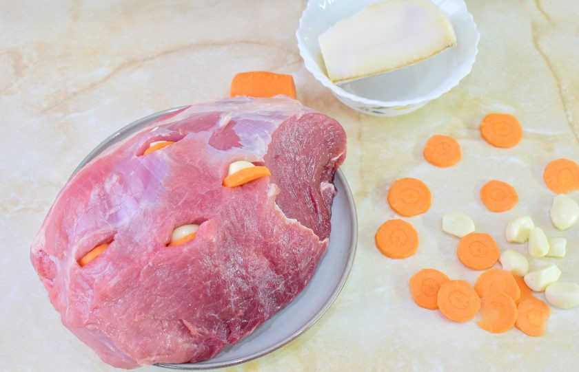 1. Этап. Мясо по-немецки: Очистите морковь и чеснок. В мясе делайте надрезы и вставляйте в них маленький кусочек сала, чеснок и морковь. При запекании сало будет делать мясо сочнее, а чеснок и морковь отдадут свой аромат.