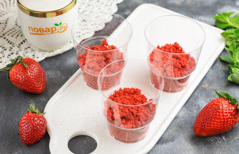 1. Этап. Трайфлы Красный бархат: На дно стаканов или чашек высыпьте часть красной бархатной крошки. По желанию можете пропитать ее любым сиропом.