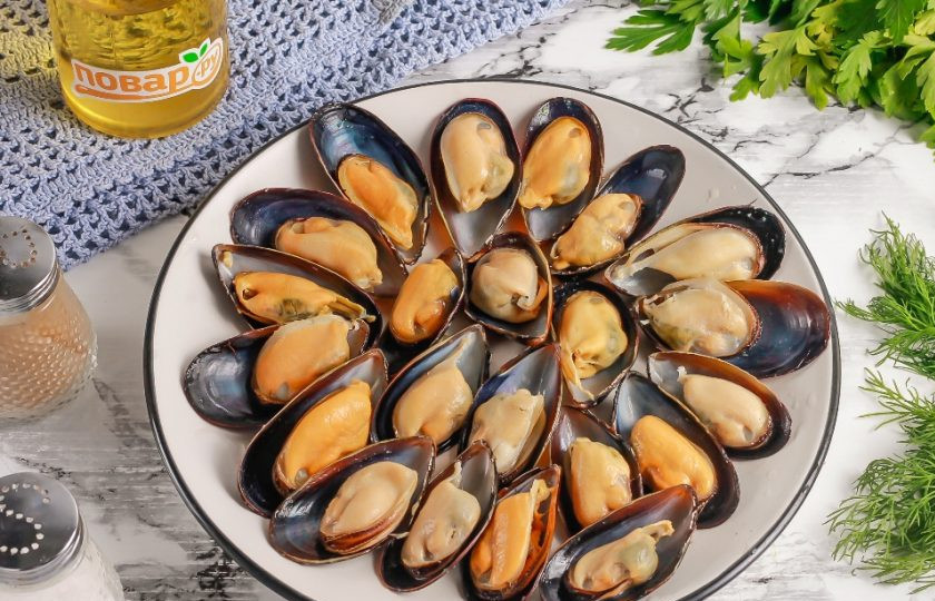 1. Этап. Мидии, запеченные с сыром в духовке: Отваренные мидии выложите на тарелку или доску, слегка остудите и раскройте, удаляя верхнюю часть ракушки. Выложите их на тарелку.