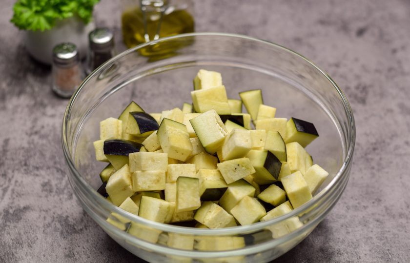 1. Этап. Жаркое из свинины с грибами и баклажанами: Баклажан ополосните и просушите, нарежьте средними по размеру кубиками. Переложите баклажан в миску, посолите и оставьте на 15 минут. Спустя время жидкость слейте и просушите баклажаны.