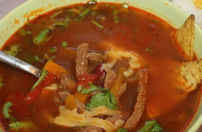 1. Этап. Мексиканский фасолевый суп: Суп подается на стол с тертым чеддером и кукурузными чипсами.