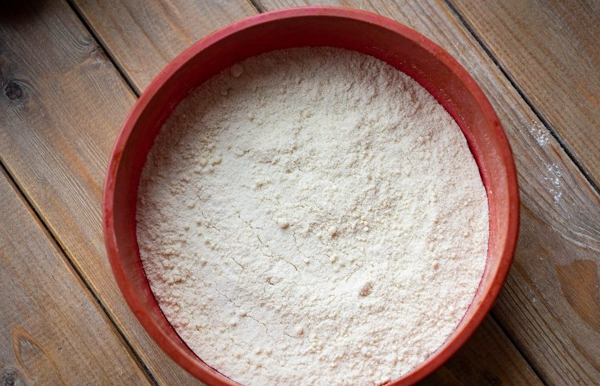 1. Этап. Насыпной пирог с яблоками без манки: На дно формы для выпекания выложите половину мучной крошки, разровняйте ее ложкой в равномерный слой.