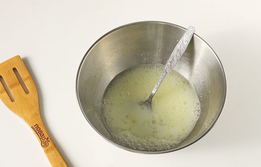 1. Этап. Вареники с сюрпризом: Пока картофель варится, приготовьте тесто. Воду налейте в глубокую миску, добавьте растительное масло, соль и яйцо. Взбейте все ложкой или венчиком.