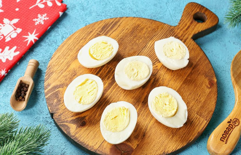 1. Этап. Закуска Дракончики на Новый год 2024: Яйца очистите от скорлупы и разрежьте их пополам.