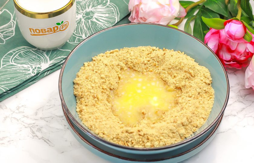 1. Этап. Чизкейк с творогом и желатином: Печенье измельчите в кухонном комбайне и залейте растопленным сливочным маслом. Тщательно перемешайте всю массу.